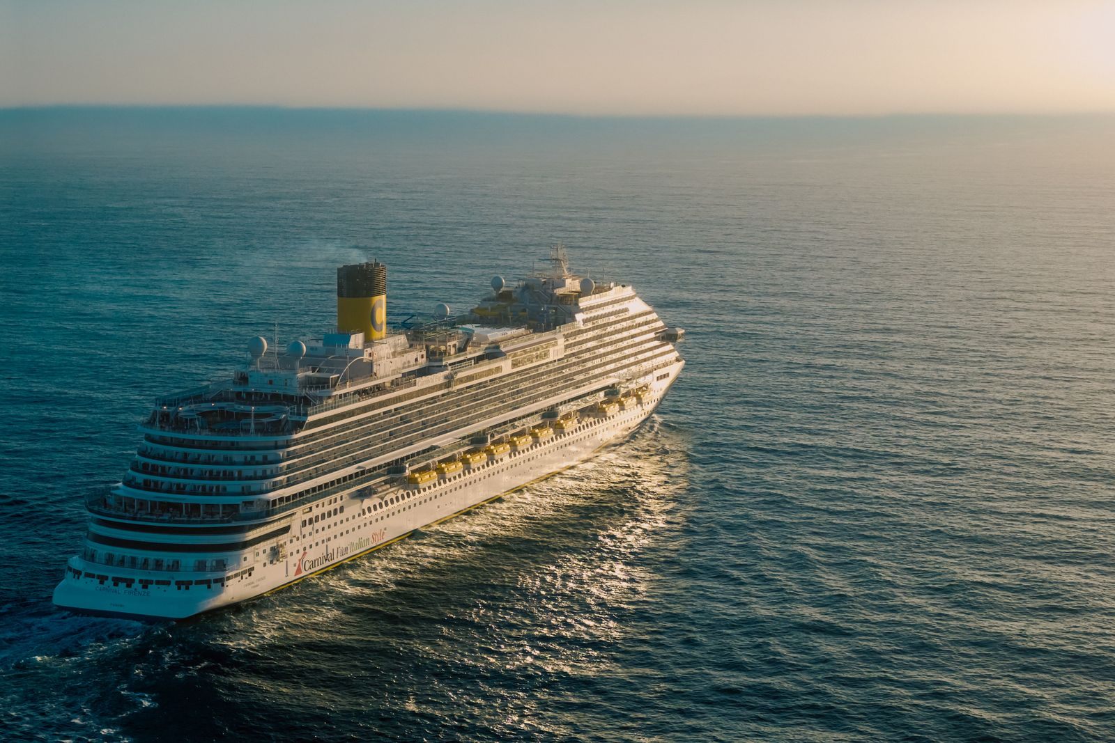 Aerial view of a cruise ship sailing across the open sea at golden hour