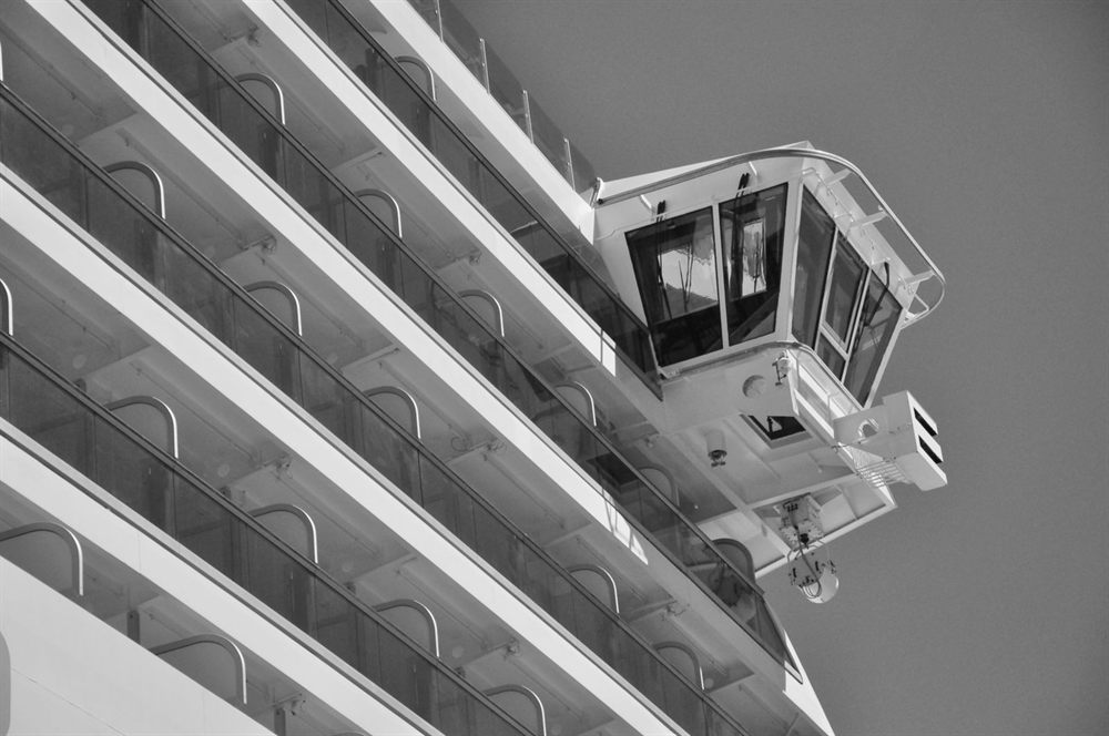 Tiers of cruise ship balconies beside the bridge wing, in black and white