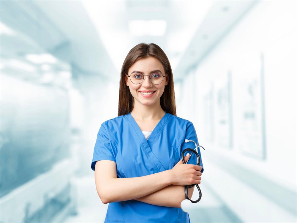 Nurse in blue scrubs smiling in a hospital corridor