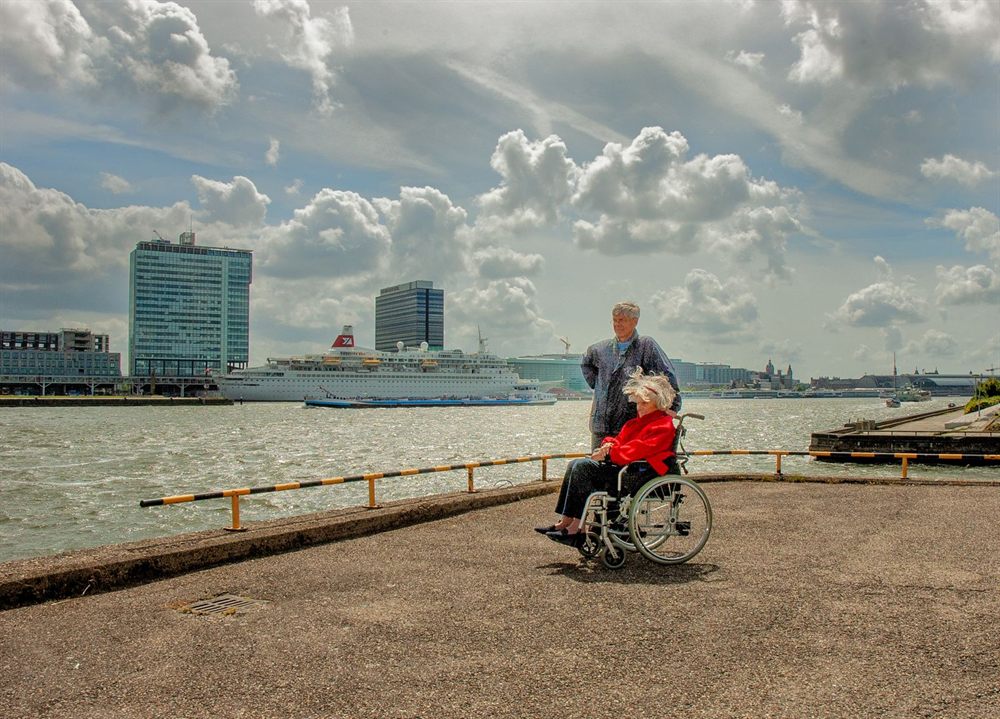 Traveler in a wheelchair on a harbor promenade with a cruise ship behind