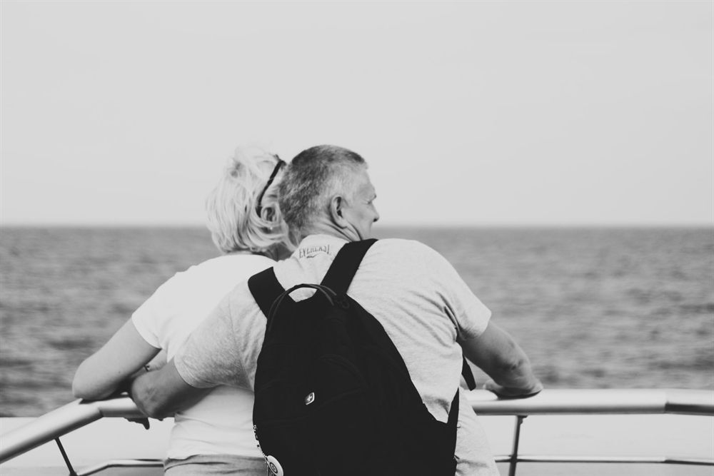 Older couple embracing at a ship&rsquo;s rail looking out to sea